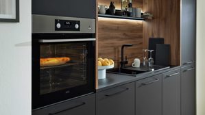 Einbauküche Interliving aus Holz in Schwarz Interliving Küche Serie 3055 mit AEG Einbaugeräten Mattschwarz & Vulkaneiche  - dreizeilig
