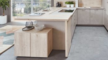 Einbauküche Nobilia® aus Holz in Holzfarben Hell nobilia® Einbauküche Riva mit JUNKER Elektrogeräten und Esstheke Beton Sand & Eiche Montreal - Stellfläche ca. 304 x 319 cm